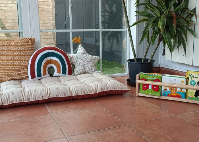Rincón de lectura Rincón de lectura estilo Montessori: colchoneta de suelo, cojines y diversos cuentos puestos a su altura para fomentar su autonomía.